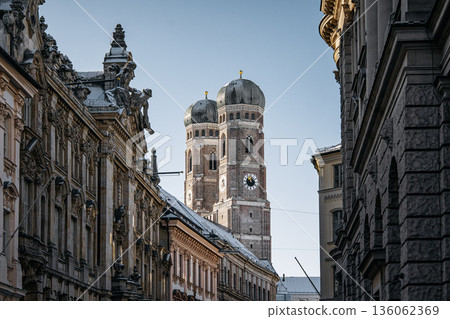 Historic Munich Old Town Street With Cathedral Of Our Dear Lady: Narrow Urban Alley Framing Iconic Twin Domed Church Towers And Traditional Bavarian Architecture 136062369