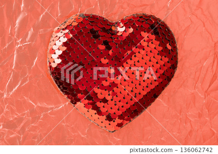 Red sequin heart symbolizing love and romance on crumpled paper 136062742