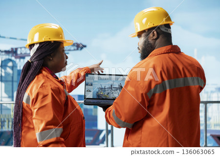 Offshore platform engineering team using laptop software interface to track production efficiency. Drilling rig crew uses notebook program dashboard to check equipment sensor readings Offshore platform engineering team using laptop software interface to track production efficiency. Drilling rig crew uses notebook program dashboard to check equipment sensor readings 136063065