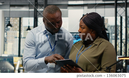 Engineers in startup office work with artificial intelligence driving market innovation. African american tech agency coworkers apply machine learning to optimize operations and efficiency, camera B Engineers in startup office work with artificial intelligence driving market innovation. African american tech agency coworkers apply machine learning to optimize operations and efficiency, camera B 136063075