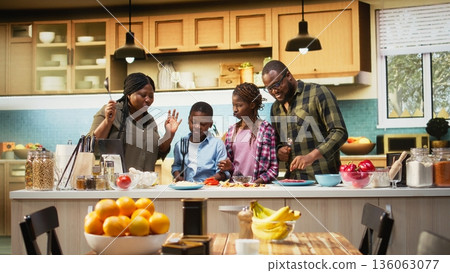African american young family singing and dancing around in the kitchen, acting silly and laughing together for fun weekend activity. Goofy kids and parents using utensils for karaoke. Camera A. African american young family singing and dancing around in the kitchen, acting silly and laughing together for fun weekend activity. Goofy kids and parents using utensils for karaoke. Camera A. 136063077