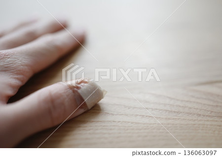 特寫鏡頭:一隻手,受傷的大拇指上纏著繃帶。 特寫鏡頭:一隻手,受傷的大拇指上纏著繃帶。 136063097