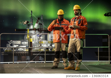 Drone deployed by offshore platform engineering team coworkers to assess hard to reach equipment areas. African american man and colleague on drilling rig fly UAV to inspect machinery components Drone deployed by offshore platform engineering team coworkers to assess hard to reach equipment areas. African american man and colleague on drilling rig fly UAV to inspect machinery components 136063314