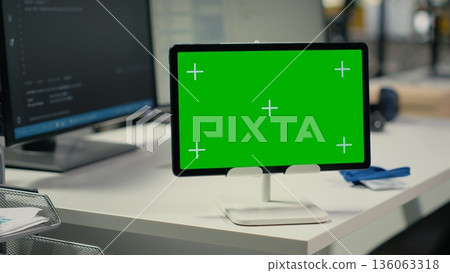 Green screen tablet in empty startup office with artificial intelligence program running on monitors. Mockup device in AI industry startup workspace leveraging deep learning tech enhancing automation 136063318