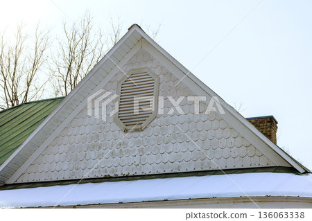 Roof with shingles, ventilation peaks over snow covered ground leafless trees. 136063338