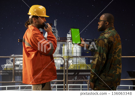 Chroma key tablet used by military unit on offshore platform for counter terrorism security. Army soldier safeguarding drilling rig operations using isolated screen device Chroma key tablet used by military unit on offshore platform for counter terrorism security. Army soldier safeguarding drilling rig operations using isolated screen device 136063348