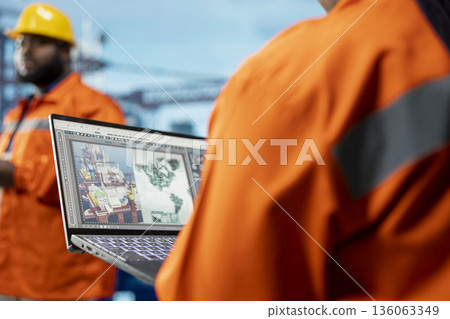 Close up of geologist on offshore platform using device to conduct subsea mapping survey, evaluating drilling sites. Expert looks at world map interface on screen with ocean oil resource locations Close up of geologist on offshore platform using device to conduct subsea mapping survey, evaluating drilling sites. Expert looks at world map interface on screen with ocean oil resource locations 136063349