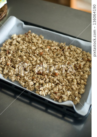 Granola spread on a plate to bake in the oven 136064190