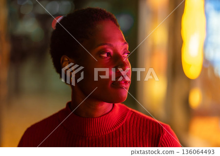 Thoughtful young woman with neon light on face at Thoughtful young woman with neon light on face at 136064493