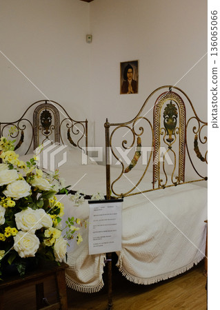 Bedroom inside Francisco and Lucia house with iron bed white linens wooden floor window light and floral arrangement heritage museum interior Fatima Portugal. High quality photo 136065066