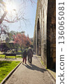 Old people walking along path beside historic aqueduct in sunny city park backlit sun and long shadows leisure scene travel lifestyle concept. High quality photo 136065081