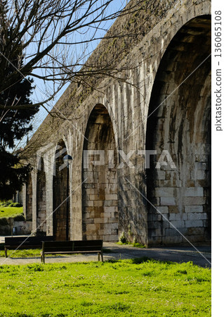 Historic stone aqueduct with arches in urban park sunny day blue sky ancient masonry architecture Portugal. High quality photo Historic stone aqueduct with arches in urban park sunny day blue sky ancient masonry architecture Portugal. High quality photo 136065108