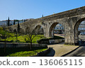 Historic stone aqueduct with arches in urban park sunny day blue sky ancient masonry architecture Portugal. High quality photo 136065115