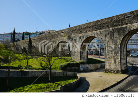 Historic stone aqueduct with arches in urban park sunny day blue sky ancient masonry architecture Portugal. High quality photo Historic stone aqueduct with arches in urban park sunny day blue sky ancient masonry architecture Portugal. High quality photo 136065115