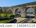 Historic stone aqueduct with arches in urban park sunny day blue sky ancient masonry architecture Portugal. High quality photo 136065119