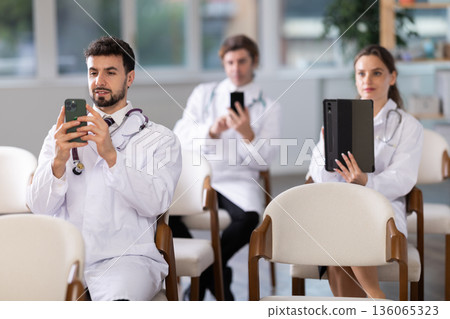 Medical students or doctors using mobile phones to scan QR-code during interactive lesson 136065323