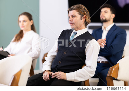 Lecture or meeting participants listen to speaker 136065334