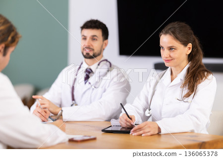 Medical professionals discussing topic during clinical meeting at table Medical professionals discussing topic during clinical meeting at table 136065378