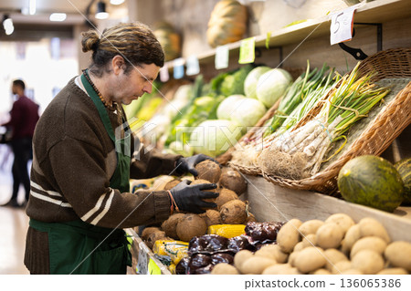 Adult man seller puts coconuts on display 136065386