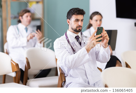 Medical students or doctors using mobile phones to scan QR-code during interactive lesson Medical students or doctors using mobile phones to scan QR-code during interactive lesson 136065405