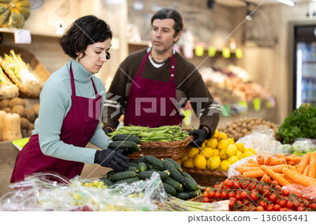 Woman seller puts cucumbers man seller puts green peas 136065441