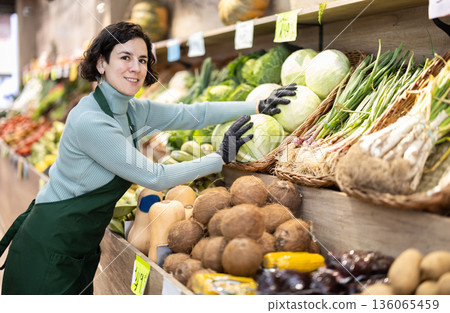Woman shop seller puts cabbage goods on display case 136065459