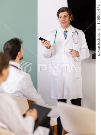Male doctor explaining medical topic to students using digital board Male doctor explaining medical topic to students using digital board 136065478