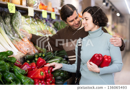 Married couple selects fresh bell peppers, tomatoes and other vegetables at supermarket counter 136065493