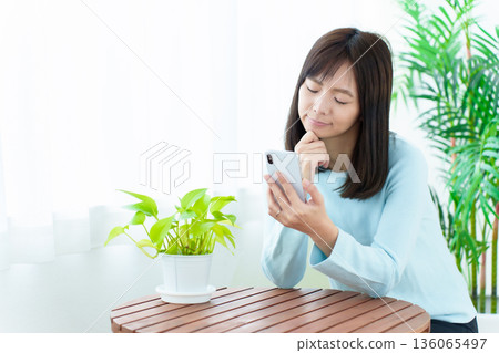 A housewife using a smartphone with a troubled look on her face 136065497