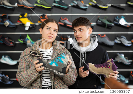 Young couple in sports shop to choose trekking winter shoes Young couple in sports shop to choose trekking winter shoes 136065507