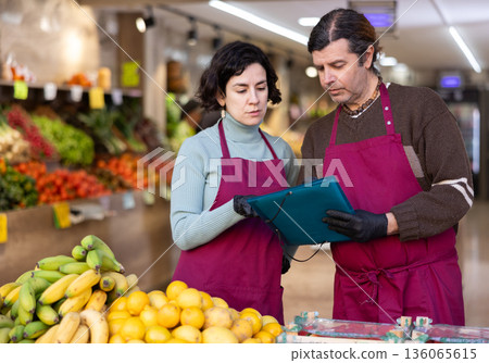 Man and woman sellers taking inventory in vegetable shop Man and woman sellers taking inventory in vegetable shop 136065615