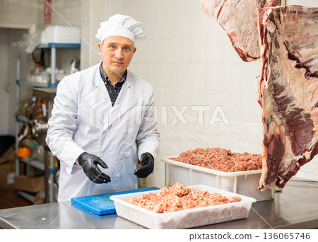 Butchery worker preparing raw minced meat for sale 136065746