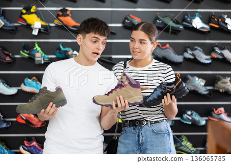 Guy with girlfriend, view specialized shoes in store, near showcase with summer trecking cross-shoes Guy with girlfriend, view specialized shoes in store, near showcase with summer trecking cross-shoes 136065785