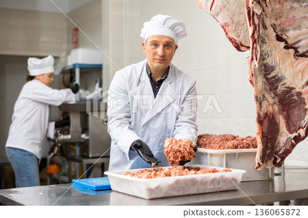 Confident male butcher showing how minced meat is prepared in butchery Confident male butcher showing how minced meat is prepared in butchery 136065872