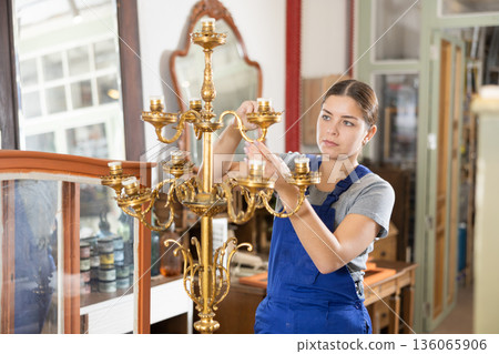 Woman restores vintage chandelier in the restoration workshop 136065906