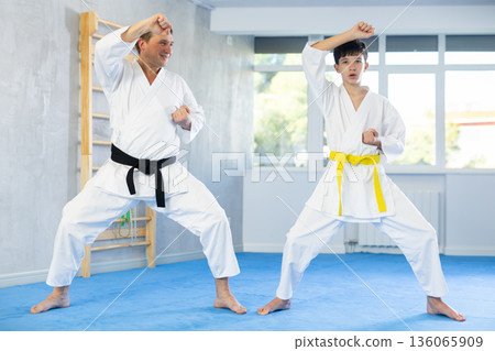 Individual karate lesson for teenager - fighting position of teenager and coach during karate training in gym 136065909