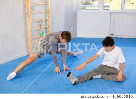 Man and boy teenager doing stretching exercises Man and boy teenager doing stretching exercises 136065910