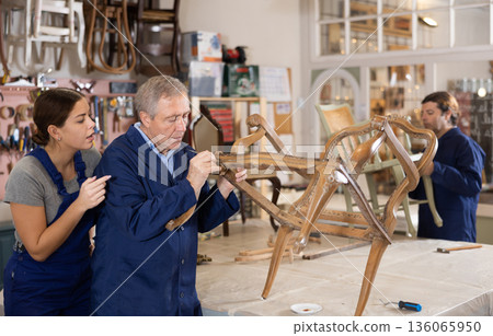 Senior male furniture maker and female apprentice working on vintage commode in workshop Senior male furniture maker and female apprentice working on vintage commode in workshop 136065950