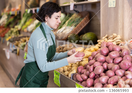 Woman shop seller puts potato goods on display case 136065993