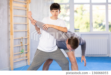 Teenage boy and middle-aged man training arm twist technique during self-defense courses Teenage boy and middle-aged man training arm twist technique during self-defense courses 136066055