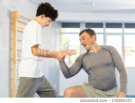Father teaching his son wrestling or self-defense techniques in gym Father teaching his son wrestling or self-defense techniques in gym 136066105