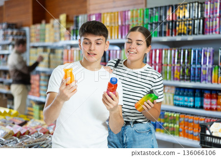 Friendly young couple choosing refreshing soft drinks in supermarket Friendly young couple choosing refreshing soft drinks in supermarket 136066106
