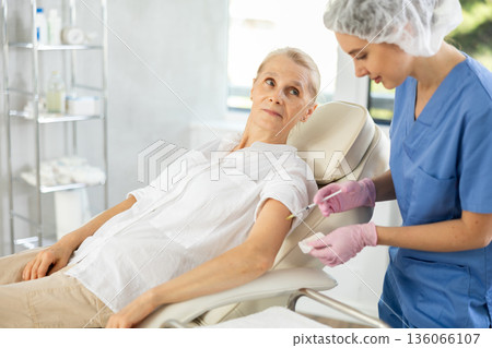 Senior woman receiving vaccine. Senior woman receiving vaccine. 136066107
