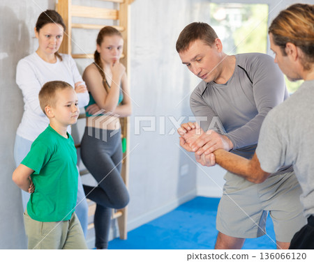 Trainer at self-defense training teaches students technique of grabbing opponent's palm on man Trainer at self-defense training teaches students technique of grabbing opponent's palm on man 136066120