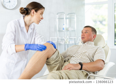 Middle-aged man patient having his knee examined by doctor Middle-aged man patient having his knee examined by doctor 136066123
