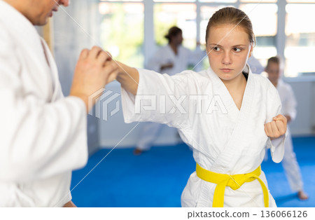 Teen girl is paired with male teacher to learn how to strike and rehearses blocking opponent 136066126