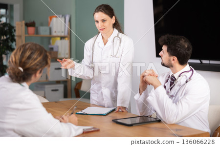 Healthcare professionals listening to standing female doctor during clinical meeting 136066228