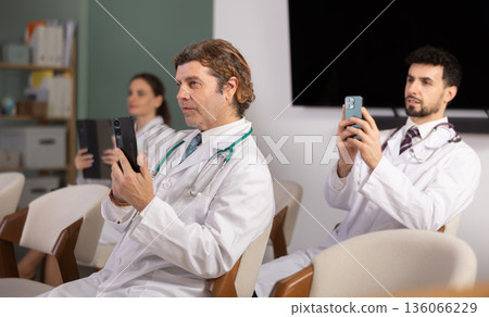 Medical students or doctors using mobile phones to scan QR-code during interactive lesson Medical students or doctors using mobile phones to scan QR-code during interactive lesson 136066229