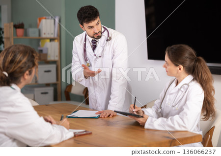 Healthcare professionals listening to standing male doctor during clinical meeting Healthcare professionals listening to standing male doctor during clinical meeting 136066237