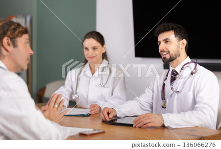 Medical professionals discussing topic during clinical meeting at table 136066276